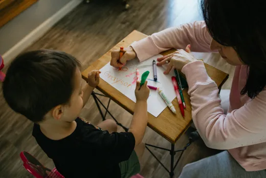 Garde d'enfants aidant un enfant à dessiner — emploi garde partagée